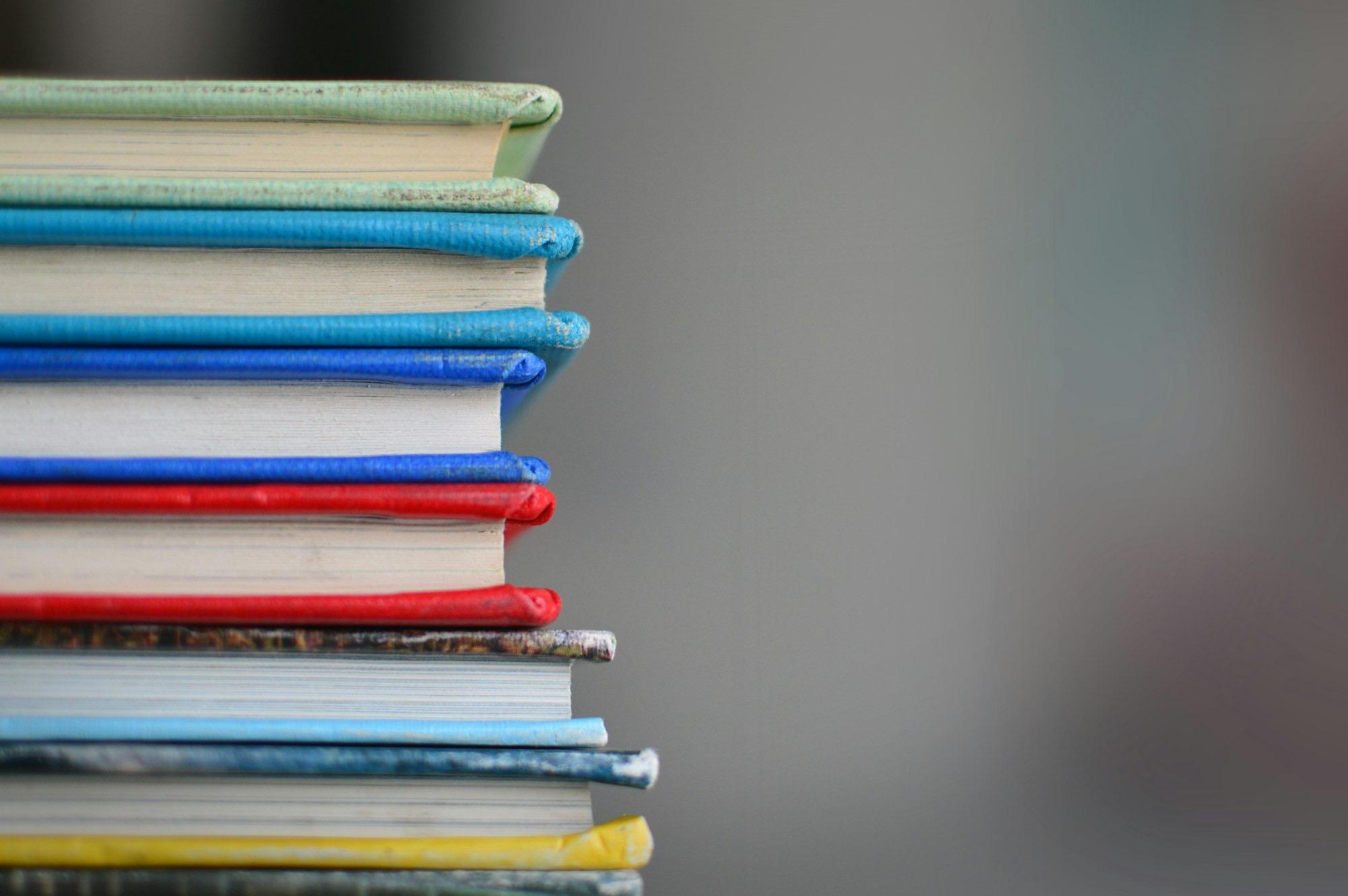 A stack of notebooks seen edge on, their spines in bright colours.