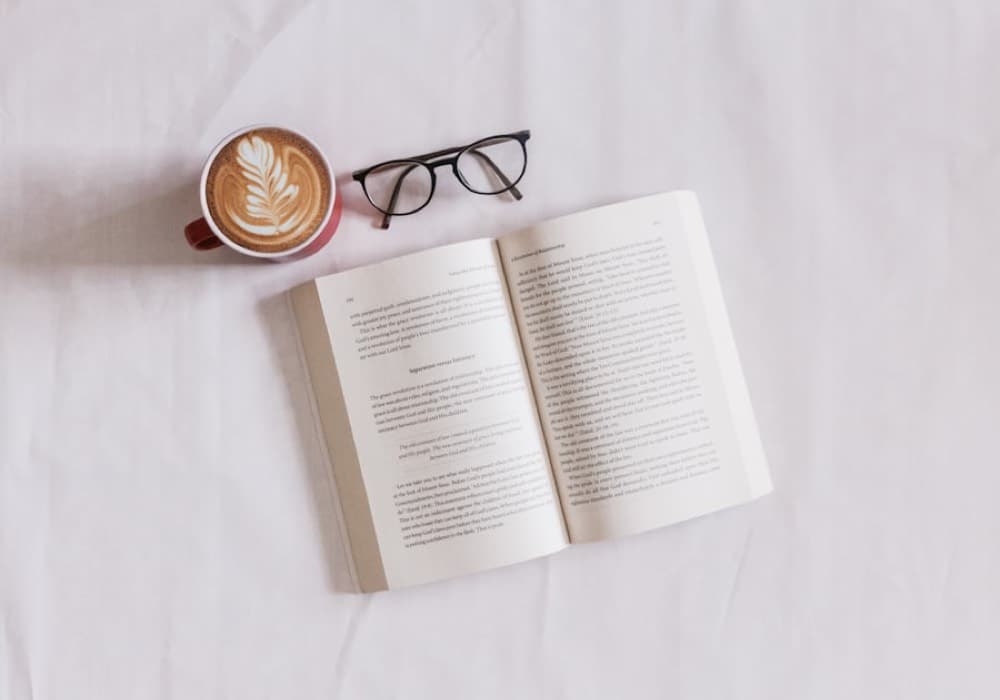 An open book and a coffee on pale linen.