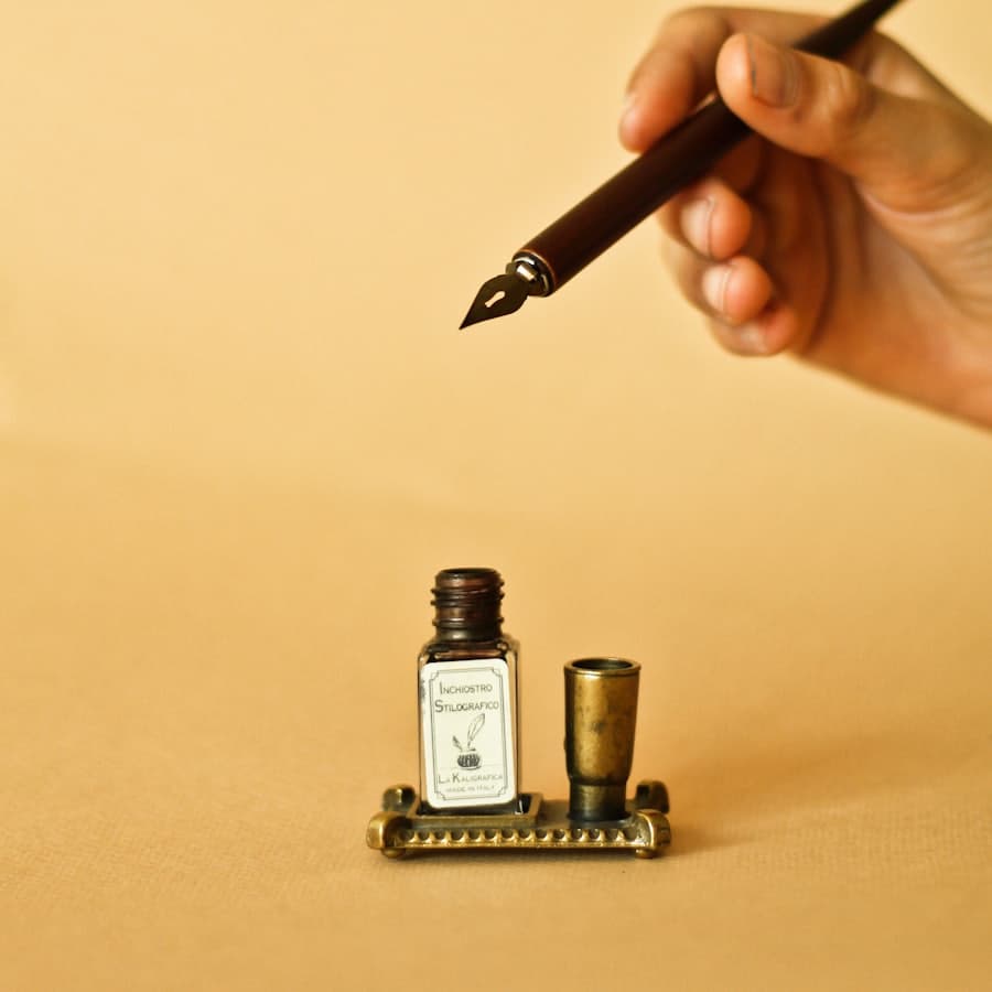 A hand writing on paper with a dip pen.